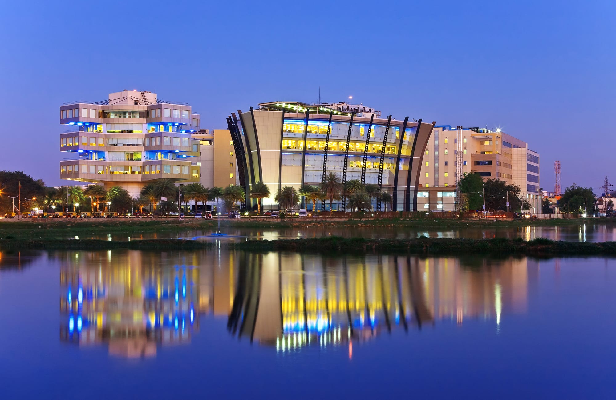 Modern buildings in Bangalore skyline at dusk reflected in a lake.
